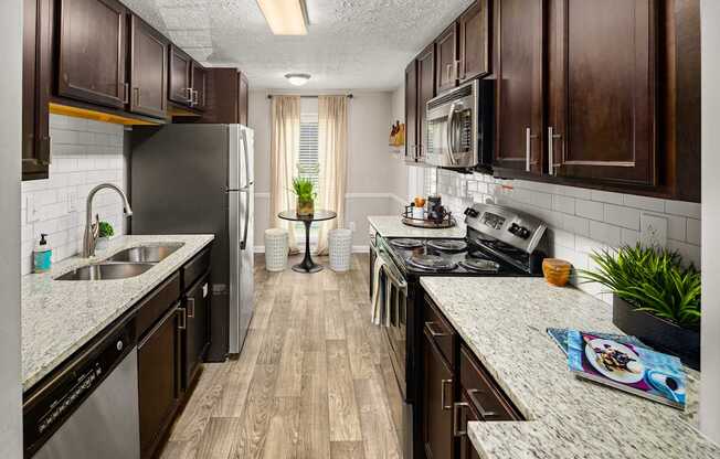 A kitchen with dark wood cabinets and a granite countertop.