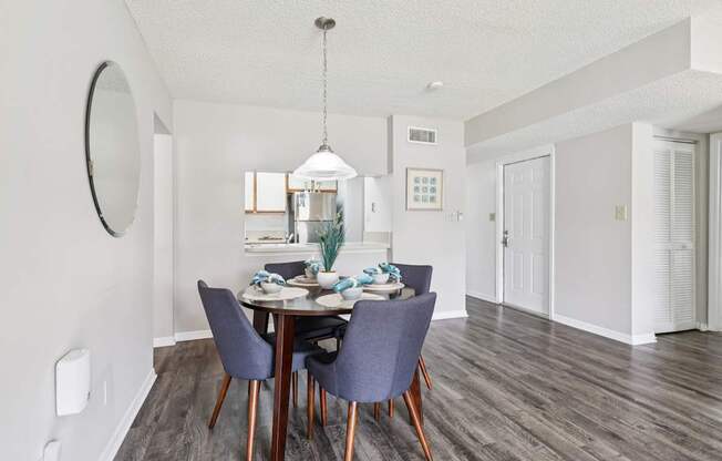 A dining room with a round mirror on the wall.