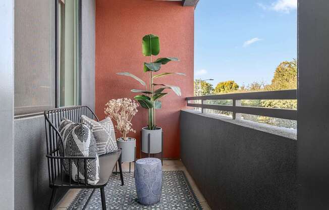 A balcony with a chair, a potted plant, and a vase.