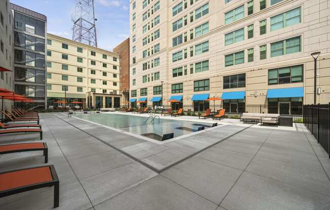 a pool area with lounge chairs and umbrellas in front of a tall building  at The Icon, Richmond, Virginia