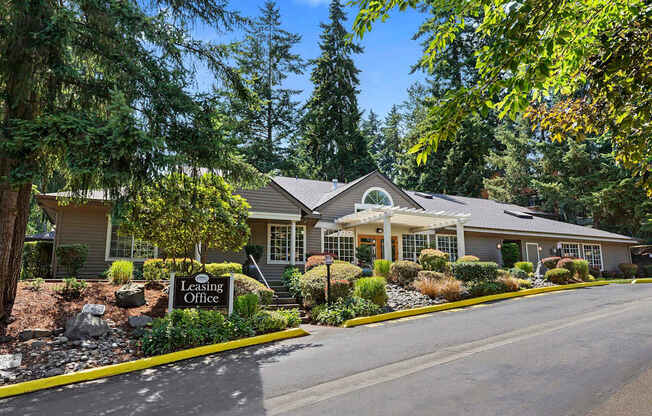 A leasing office is situated in front of a house with a landscaped yard.