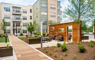 a courtyard with a wooden walkway and benches in front of an apartment building