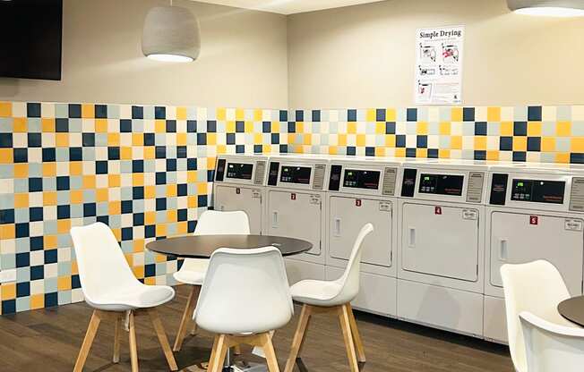 A room with a checkered wall and a white table with chairs.