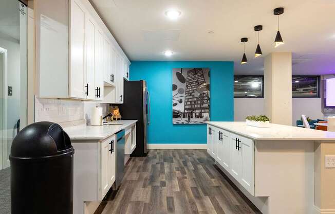 a kitchen with white cabinets and a blue wall