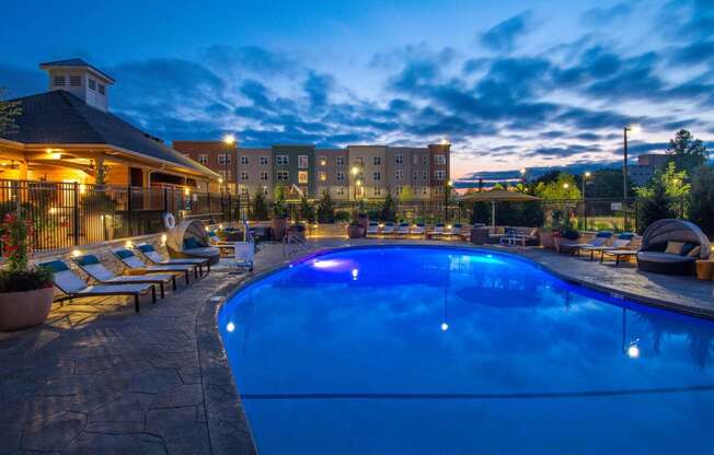 a swimming pool at night with a hotel in the background