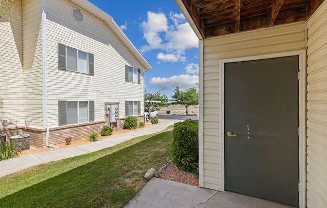 a garage door on the side of a house with a lawn and a sidewalk