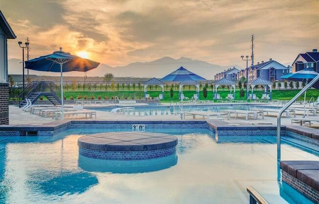 a swimming pool at sunset with mountains in the background  at Affinity 56 Apartments in West Jordan, Utah