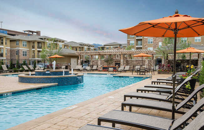 A pool area with sun loungers and umbrellas.