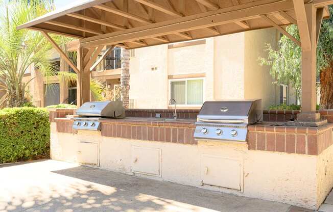 an outdoor kitchen with two grills and a sink at Oak Terrace Senior Apts, Hemet, CA