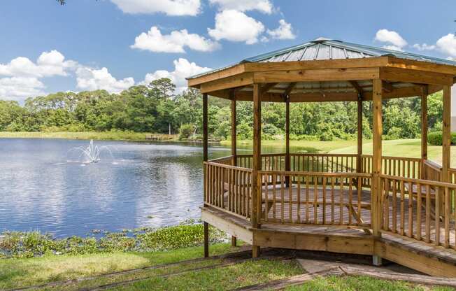 a gazebo by a pond with a fountain