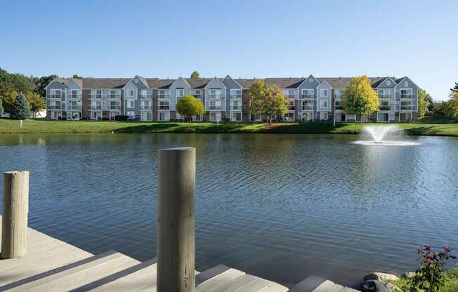 A lake in front of apartment buildings with a fountain in the middle.