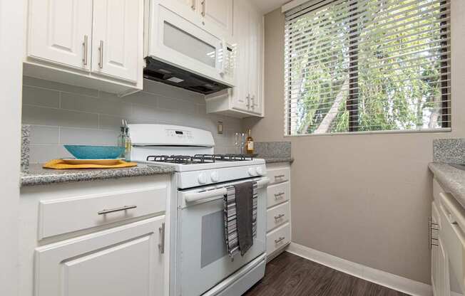A white stove and microwave in a kitchen with white cabinets.
