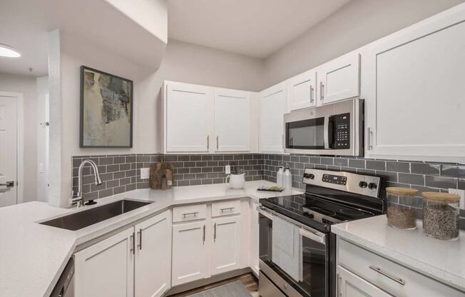 a kitchen with white cabinets and black appliances