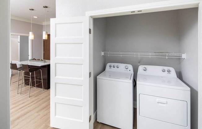 A white door is open to a laundry room with a washer and dryer.