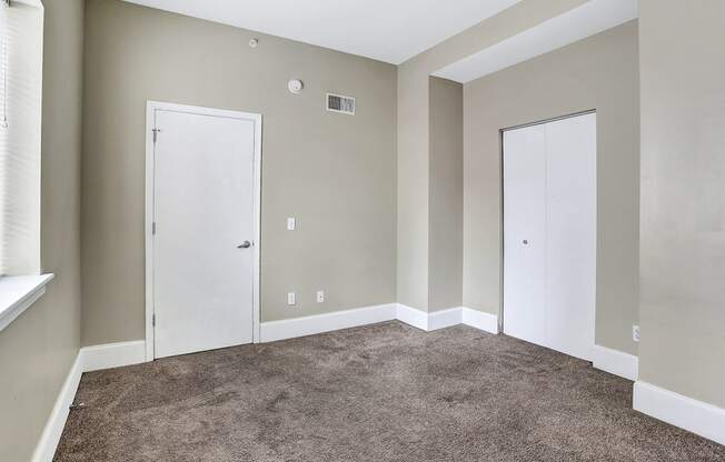 an empty room with carpet and two doors