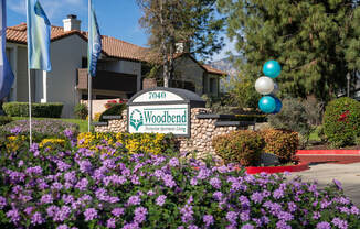A sign for Woodbend Demonstration Farm is in front of a building.