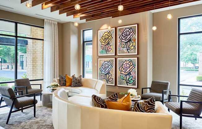 A living room with a white couch and a painting of a rose on the wall.