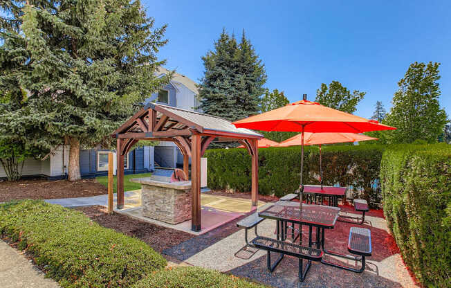 A picnic area with a table and chairs under a red umbrella.