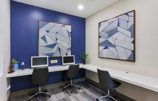 three computers in a room with a blue accent wall