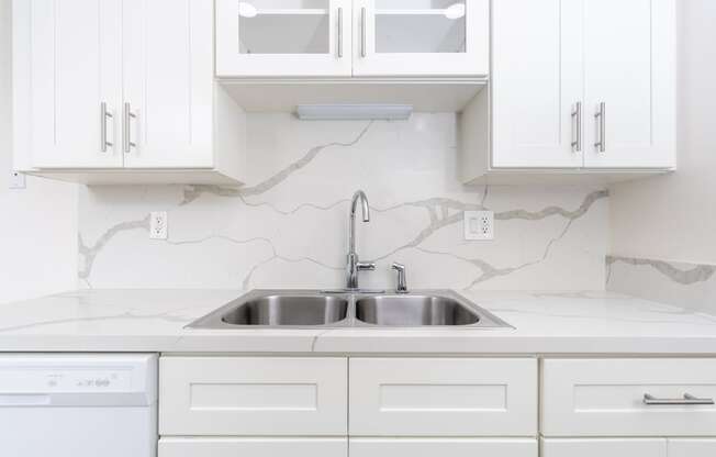 a white kitchen with a sink and white cabinets