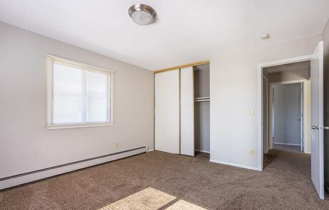 an empty living room with carpet and a door to a closet