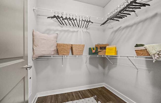 A white closet with a basket and a yellow box on the shelf.
