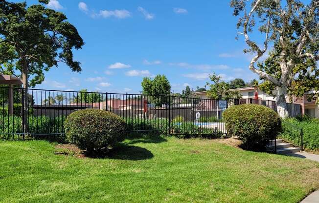 Beautiful trees and lush gardens around swimming pool at Plaza Verde Apartments in Escondido, California.