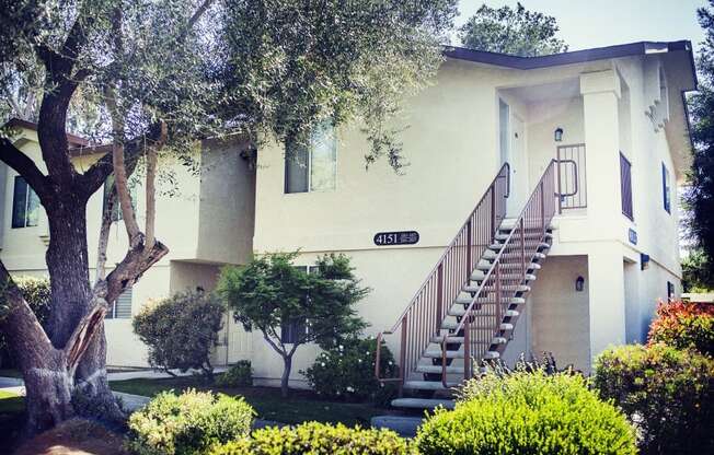 a house with a staircase and trees in front of it