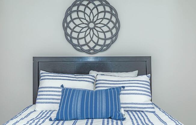 A bed with blue and white striped pillows and a circular wall decoration above it.