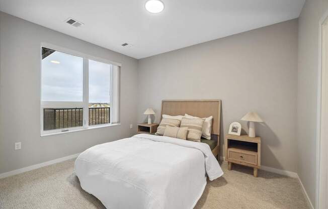 a white bedroom with a large window and a bed