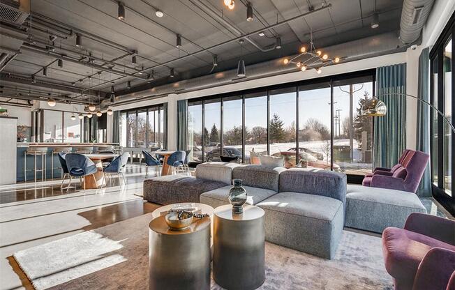 a living room with couches and chairs and large windows