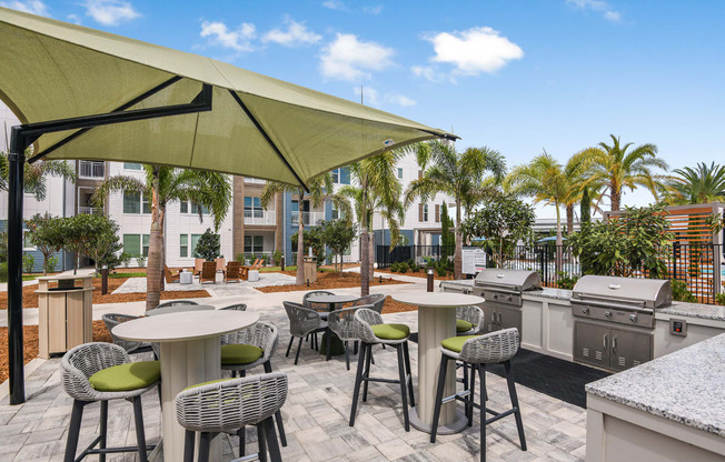 a patio with tables and chairs and a grill