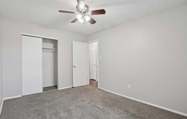 A room with a ceiling fan and carpeted floor.
