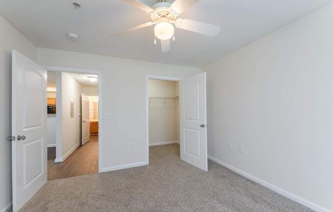 A room with a ceiling fan and carpeted floor.