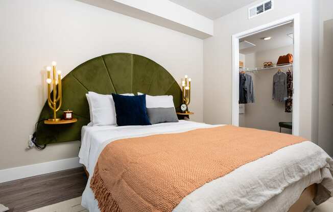 One-Bedroom Apartments in South Park Los Angeles, CA - The Emerald - Furnished Bedroom with Green Headboard, Spacious Closet, and Luxury Plank Flooring