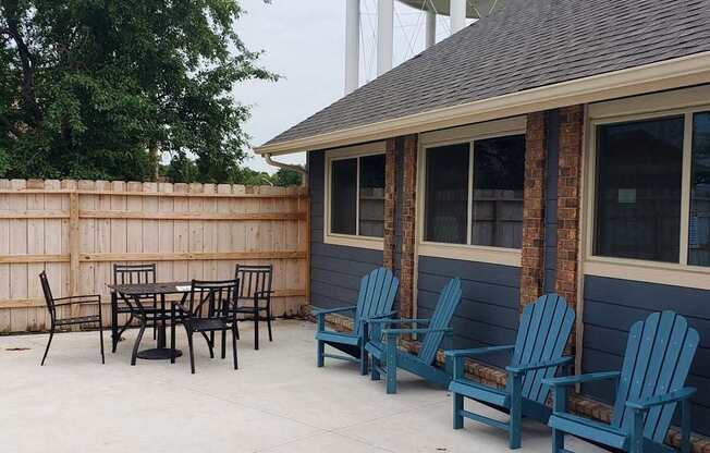 A patio with blue chairs and a table.