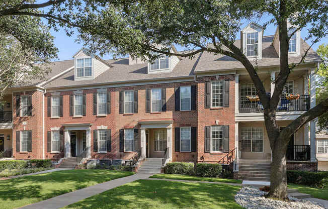 A red brick house with a tree in front.