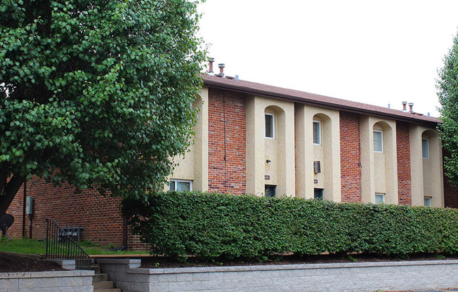 a large brick building with a hedge in front of it