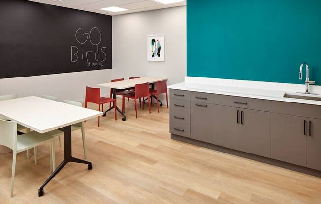 A room with a white table and chairs and a blackboard with the words "GO BIRDS" written on it.