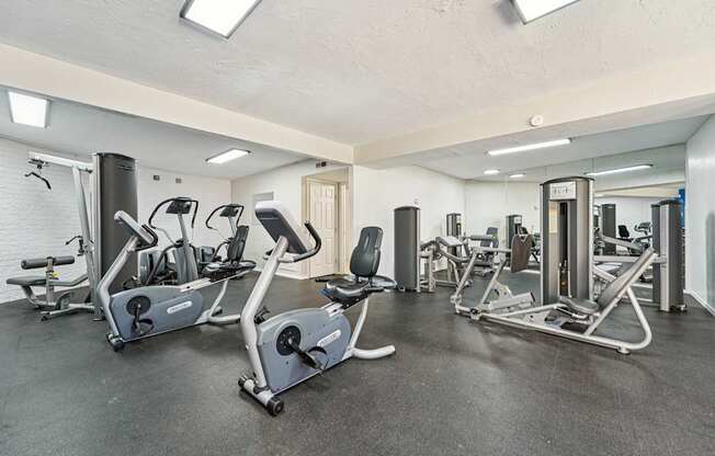 A gym with a variety of exercise equipment including treadmills, stationary bikes, and weight machines.