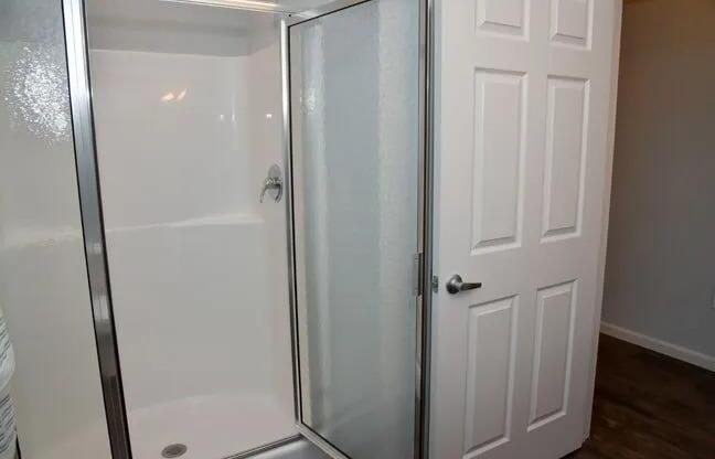 a bathroom with a shower and a white door