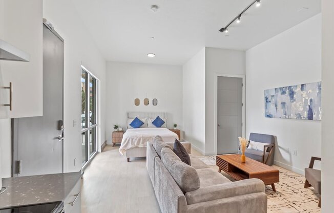 A modern living room with a grey couch and a large painting on the wall.