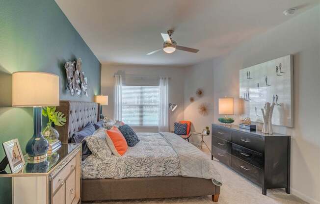 A bedroom with a bed, dresser, and ceiling fan.