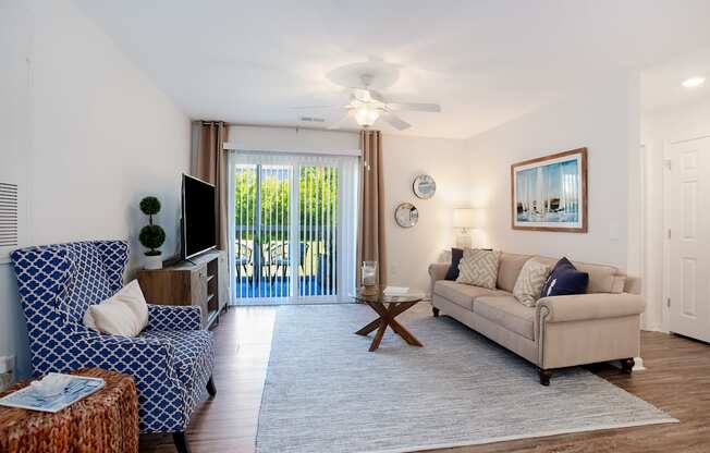 A living room with a blue patterned couch and a beige couch.