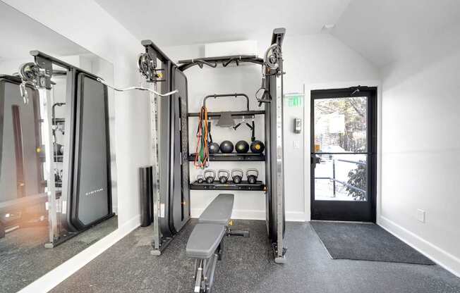 A gym with a bench, weights, and a mirror.