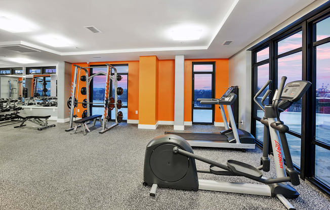 a gym with exercise equipment and windows with a view of the water