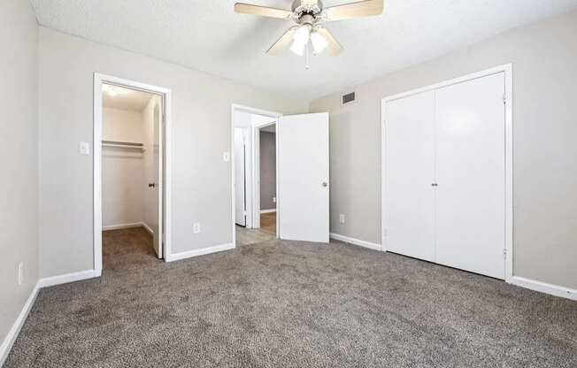 A room with a ceiling fan and carpeted floor.