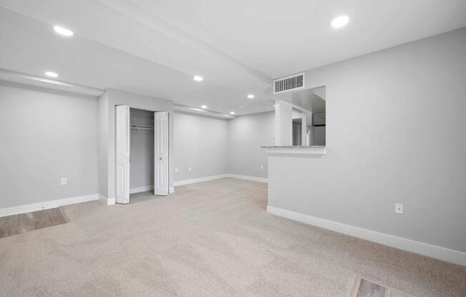 A spacious room with a carpeted floor and a doorway leading to another room.