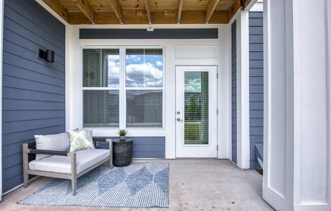 a front porch with a chair and a rug and a door