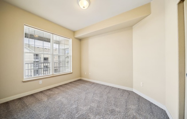 an empty living room with a large window and carpeting